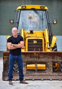 Read more about the article Ross Kemp pictured during his visit to JCB with the backhoe  loader used by the Millennium Dome raiders
